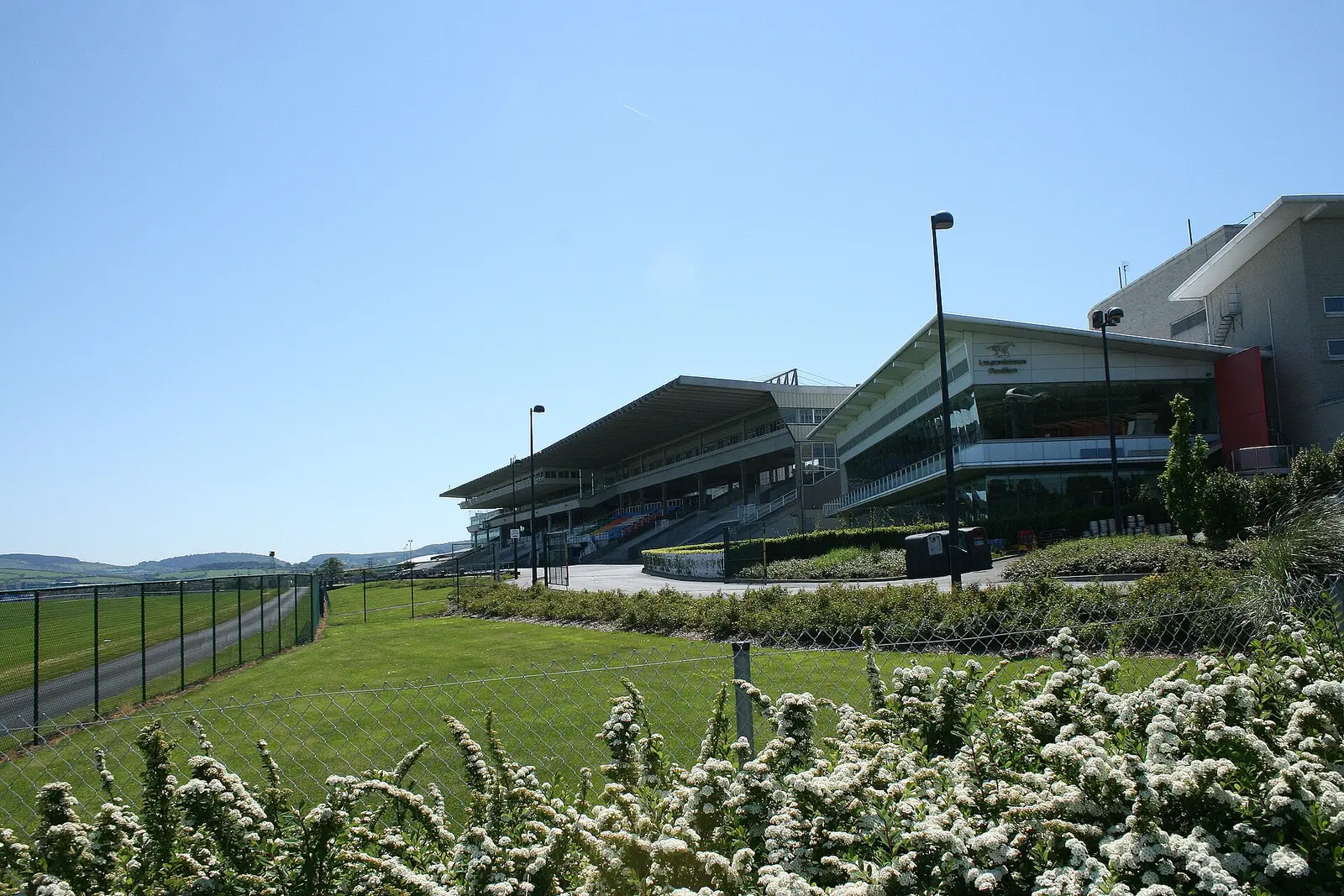 Leopardstown Racecourse grandstand beyond flower beds under a blue sky